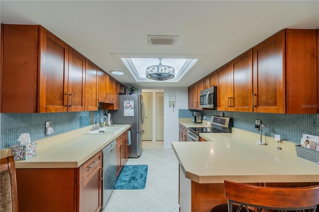 kitchen featuring kitchen peninsula, stainless steel appliances, tasteful backsplash, and sink