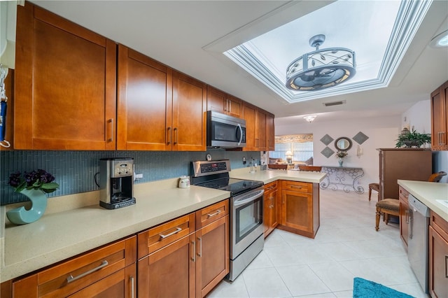 kitchen featuring stainless steel appliances, decorative backsplash, light stone counters, and kitchen peninsula