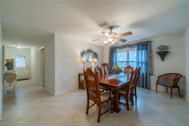 tiled dining room with a textured ceiling and ceiling fan