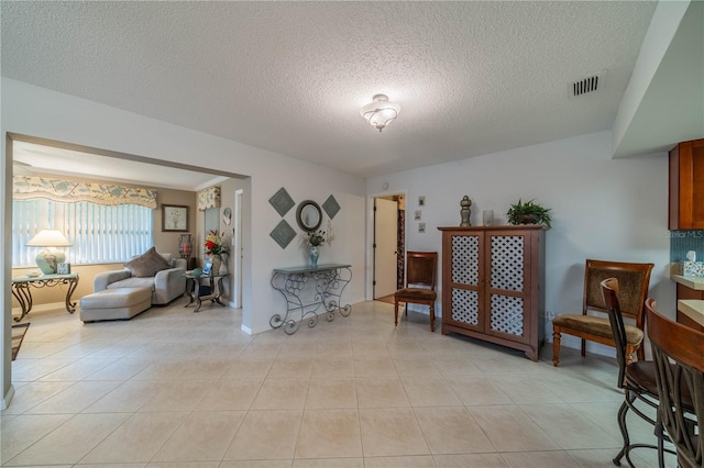 living area featuring a textured ceiling and light tile patterned floors