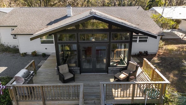 rear view of property featuring french doors, a wooden deck, and a sunroom