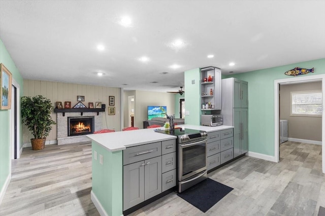 kitchen with light hardwood / wood-style floors, stainless steel electric range oven, and ceiling fan