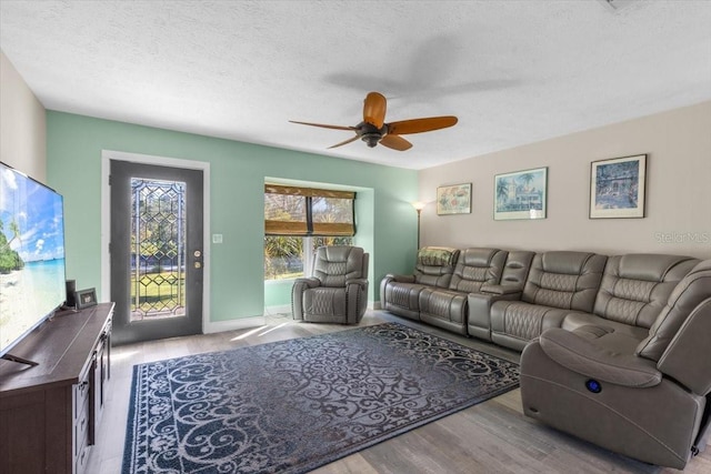 living room featuring ceiling fan, a textured ceiling, and light hardwood / wood-style flooring