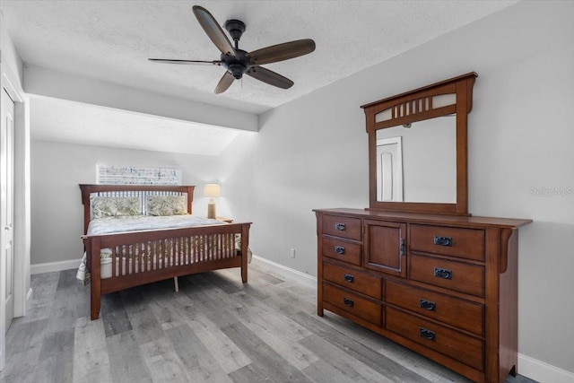 bedroom featuring ceiling fan, light hardwood / wood-style floors, a textured ceiling, and vaulted ceiling