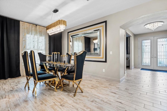 dining room featuring light wood-type flooring, french doors, and a chandelier