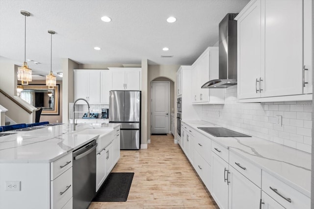 kitchen featuring appliances with stainless steel finishes, decorative backsplash, wall chimney exhaust hood, white cabinets, and light stone counters