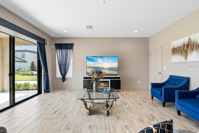 living room featuring a textured ceiling, a healthy amount of sunlight, and light hardwood / wood-style floors