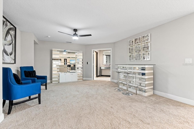 living area with carpet floors, ceiling fan, and a textured ceiling