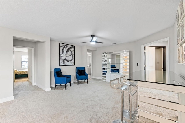 sitting room with a textured ceiling, ceiling fan, and carpet flooring