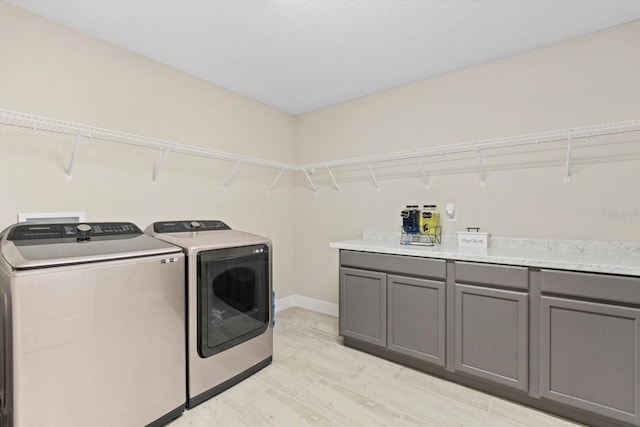 laundry room featuring light hardwood / wood-style flooring, washer and dryer, and cabinets