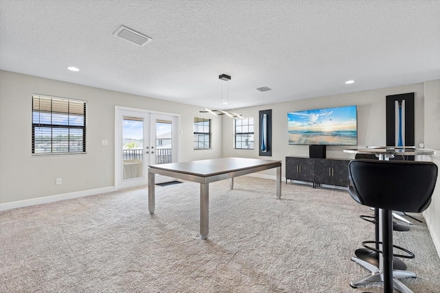 carpeted office space with french doors, a wealth of natural light, and a textured ceiling