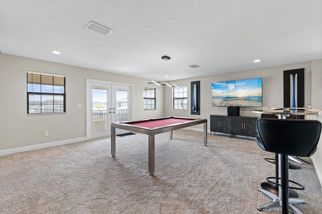 recreation room featuring a textured ceiling, pool table, light colored carpet, and french doors