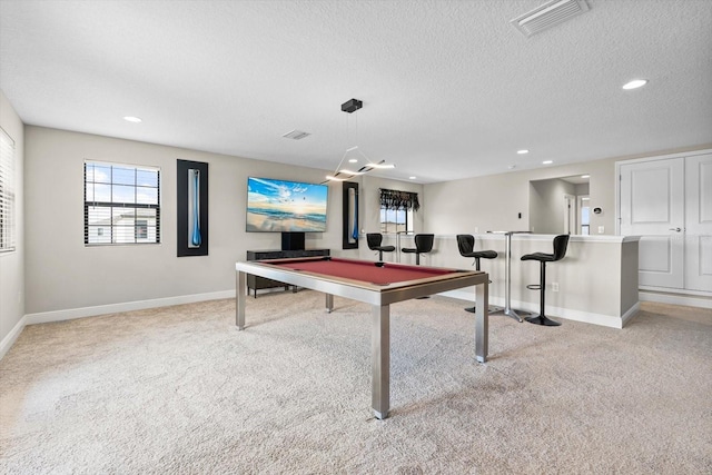 recreation room with light colored carpet, a textured ceiling, pool table, and indoor bar