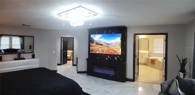 bedroom with ensuite bathroom and a textured ceiling