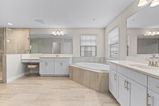 bathroom with a textured ceiling, independent shower and bath, and vanity