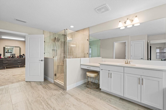 bathroom with a shower with shower door, a textured ceiling, and vanity