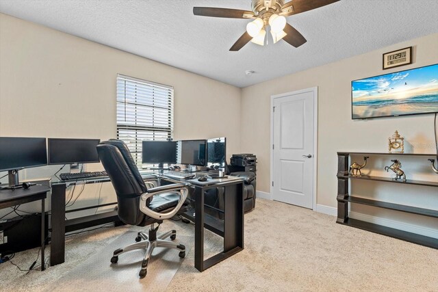 carpeted home office with ceiling fan and a textured ceiling