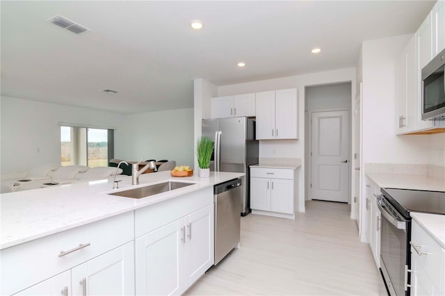 kitchen featuring light stone countertops, white cabinets, appliances with stainless steel finishes, and sink