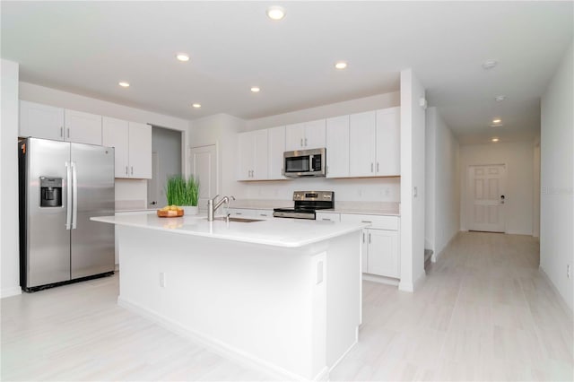 kitchen featuring appliances with stainless steel finishes, sink, white cabinetry, and a kitchen island with sink