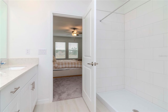 bathroom featuring ceiling fan, tiled shower, and vanity