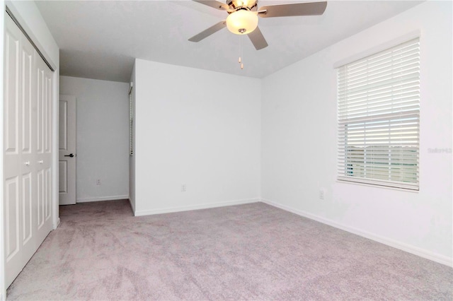 unfurnished bedroom with ceiling fan, light carpet, and a closet