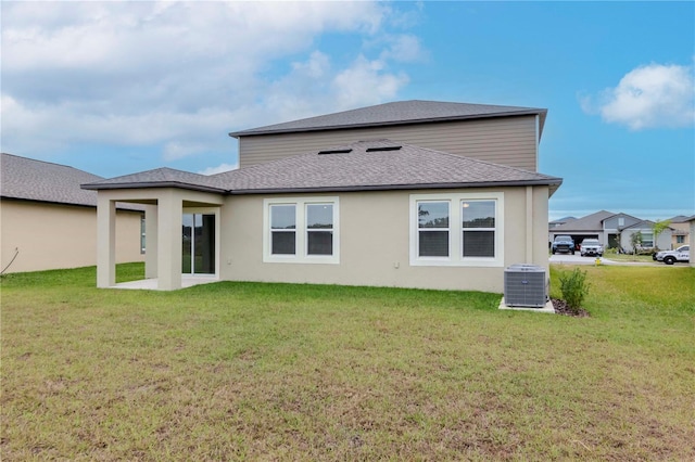 rear view of property with central AC and a yard