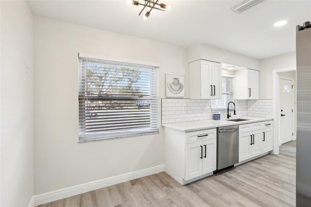 kitchen featuring dishwasher, backsplash, sink, light wood-type flooring, and white cabinetry