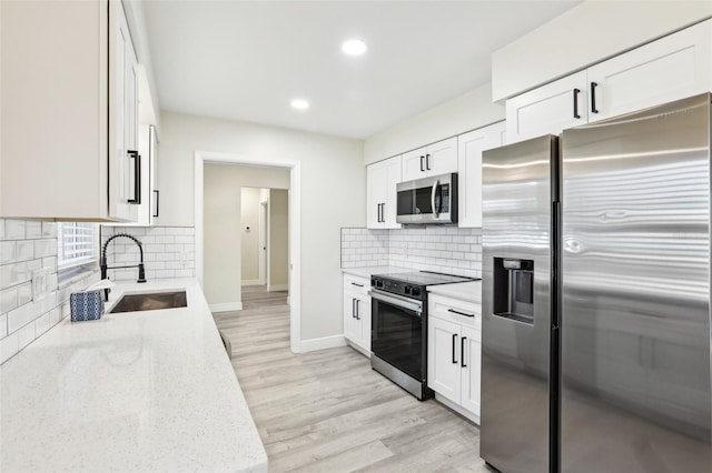 kitchen featuring decorative backsplash, appliances with stainless steel finishes, light stone countertops, sink, and white cabinetry