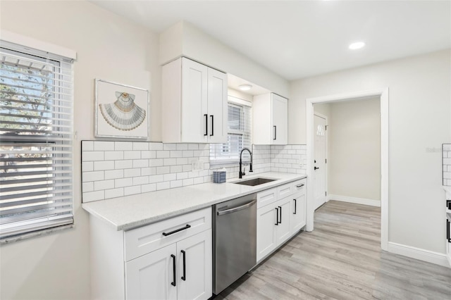 kitchen featuring backsplash, stainless steel dishwasher, sink, white cabinets, and light hardwood / wood-style floors