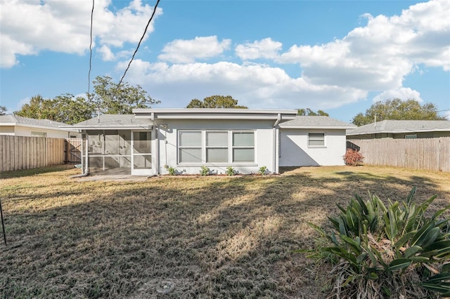 back of property with a lawn and a sunroom