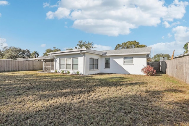 rear view of property featuring a sunroom and a yard