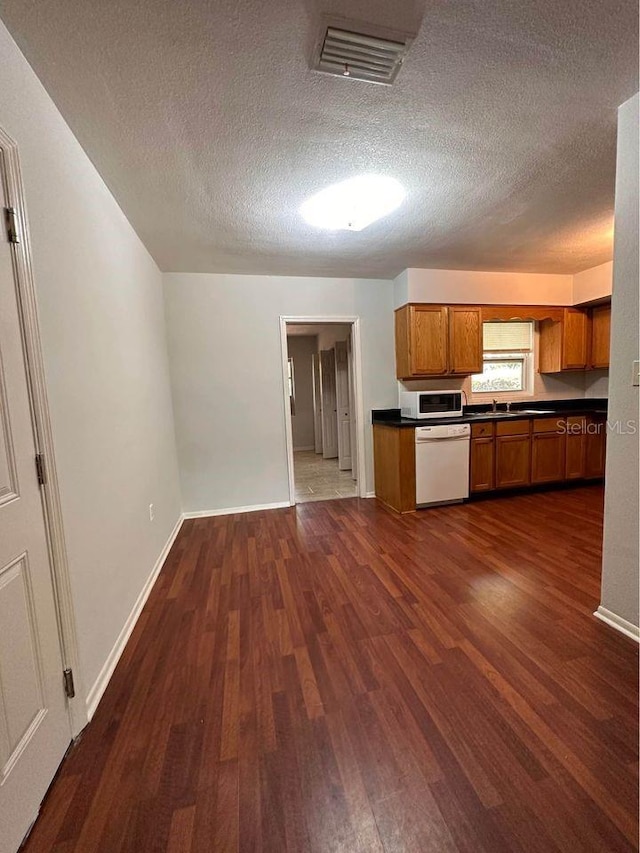 kitchen with dark hardwood / wood-style flooring, white appliances, and a textured ceiling