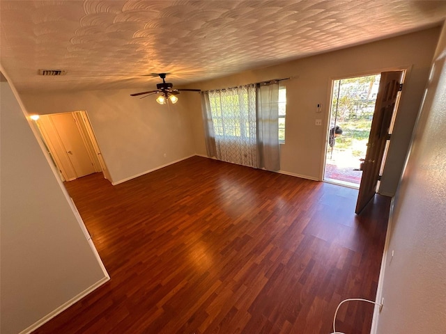 unfurnished living room featuring a textured ceiling, dark hardwood / wood-style flooring, and ceiling fan