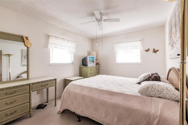 carpeted bedroom with multiple windows, a textured ceiling, and ceiling fan