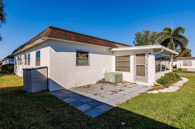 back of house featuring a lawn, central AC, and a patio