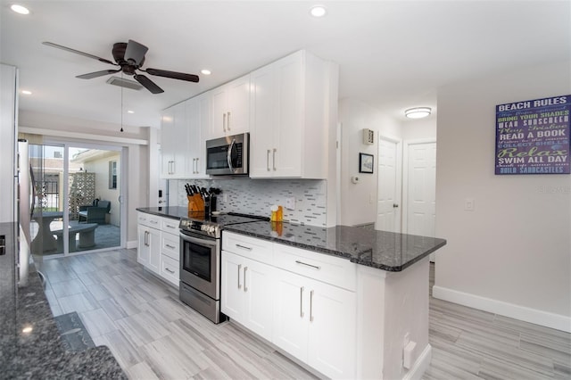 kitchen with white cabinets, appliances with stainless steel finishes, dark stone countertops, and ceiling fan