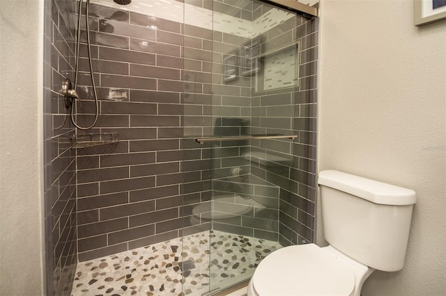 bathroom featuring toilet and a shower with door