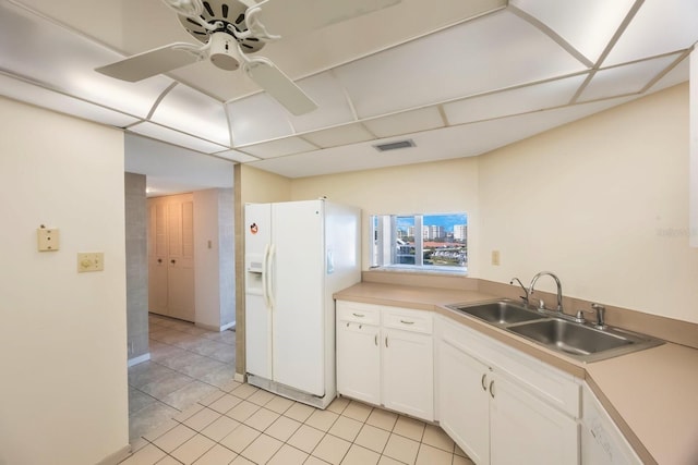 kitchen with sink, light tile patterned floors, ceiling fan, white cabinetry, and white fridge with ice dispenser