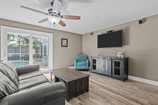 living room with a textured ceiling, light hardwood / wood-style flooring, and ceiling fan