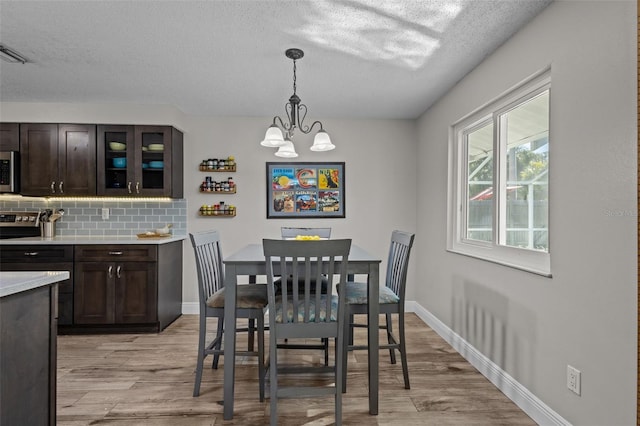 dining space with light hardwood / wood-style floors, a textured ceiling, and a chandelier