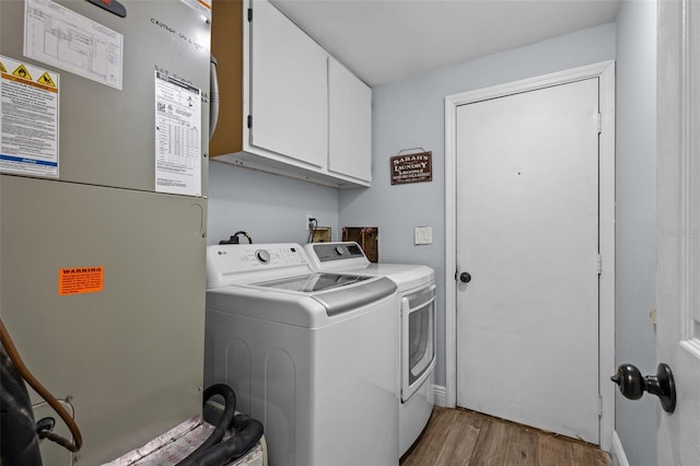 clothes washing area with cabinets, light wood-type flooring, heating unit, and separate washer and dryer