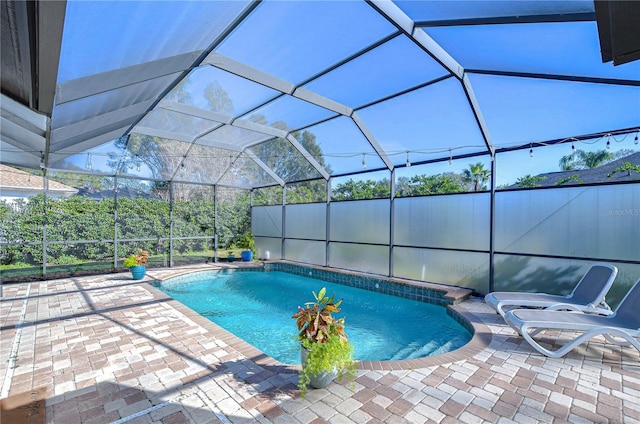 view of swimming pool with glass enclosure and a patio area