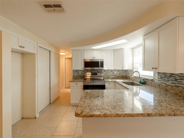 kitchen featuring sink, stainless steel appliances, light stone counters, backsplash, and white cabinets