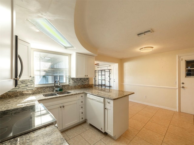 kitchen with white dishwasher, sink, light tile patterned floors, white cabinetry, and kitchen peninsula