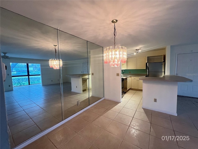 kitchen with ceiling fan with notable chandelier, black fridge, hanging light fixtures, and light tile patterned flooring