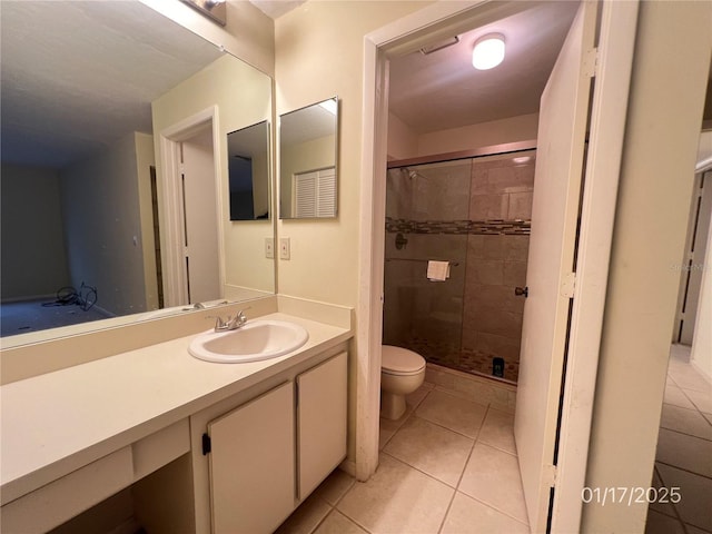 bathroom with a shower with shower door, toilet, vanity, and tile patterned flooring