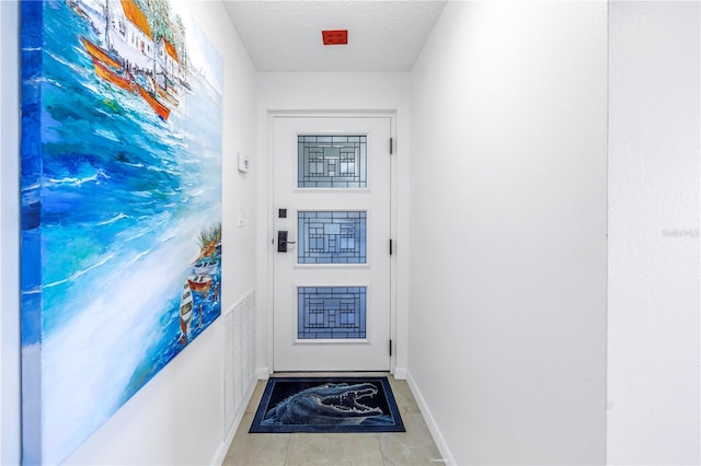 entryway with a textured ceiling and light tile patterned floors