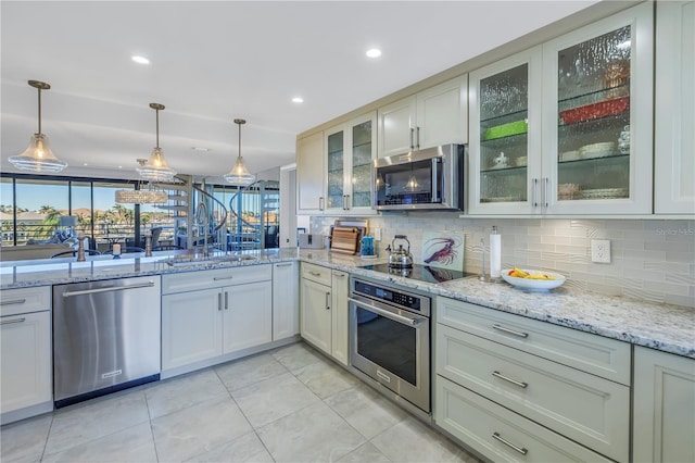 kitchen with sink, decorative light fixtures, light stone counters, and appliances with stainless steel finishes