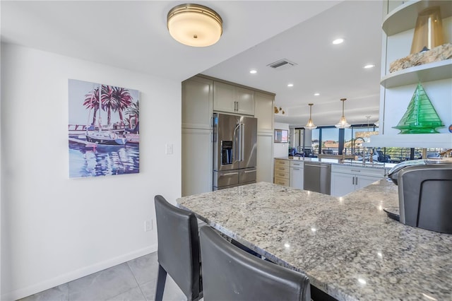 kitchen featuring light stone counters, light tile patterned floors, kitchen peninsula, pendant lighting, and appliances with stainless steel finishes