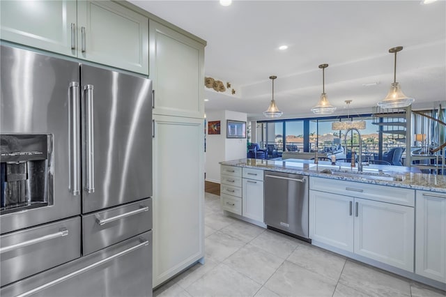 kitchen with stainless steel appliances, sink, light tile patterned floors, hanging light fixtures, and light stone countertops